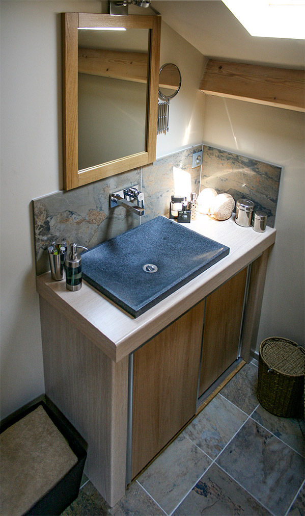 Réalisation d'un meuble de salle de bains en bois clair avec deux portes coulissantes, surmonté d'une vasque déco plate couleur ardoise.
