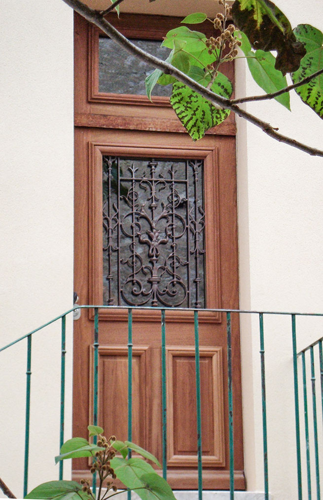 Vue, posée, d'une porte d'entrée traditionnelle vitrée réalisée en acajou iroko.